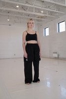 Ariane Levasseur Ariane Levasseur dans un studio de danse aux murs blancs et aux petites fenêtres carrées près du plafond avec des poutres métalliques.