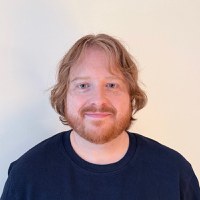 Portrait d'Aaron Labbé devant un mur blanc, vêtu d'un t-shirt bleu foncé
