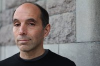 A headshot of Marc-Pierre Verge in a black t-shirt standing in front of a cinderblock wall. 