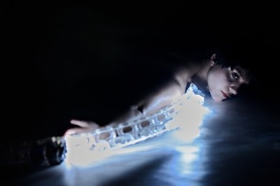 A dancer lying on the floor with a motion-sensitive digital instrument during a performance of Les Gestes