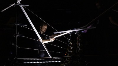 Performer playing the giant harp which is lit up