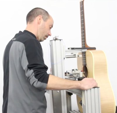 Technician preparing a guitar for measurement with the robotic strumming system at Godin Guitar's factory in La Patrie, Quebec