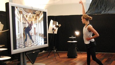 A dancer in front of a screen showing another dancer in a different location