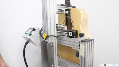 Une guitare dans un système de mesure équipé d'un dispositif robotisé de grattage, à l'usine Godin de La Patrie, au Québec.