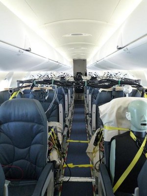 Une cabine d'avion montrant les sièges et l'allée, équipée de dispositifs de mesure acoustique installés un peu partout
